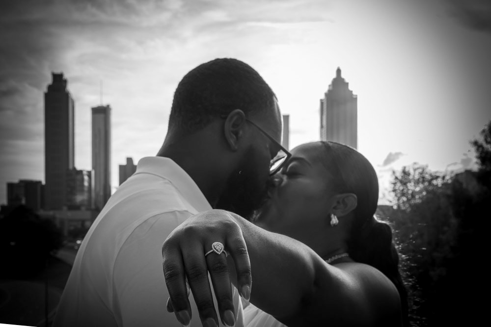 Black and white engagement photo with city skyline backdrop