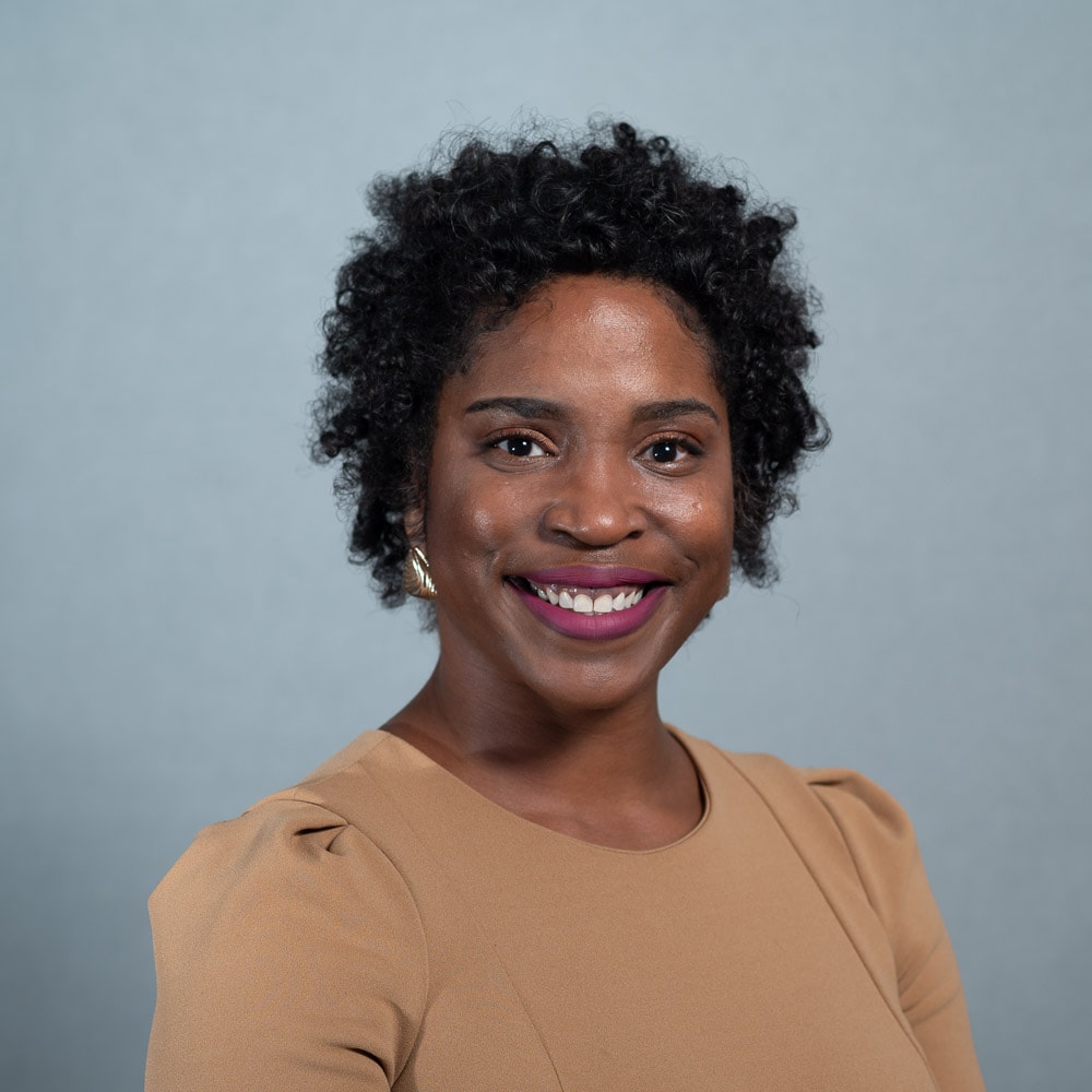 Professional headshot of woman in tan top with natural hair