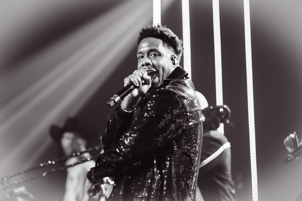 Black and white performer on stage with dramatic beam lighting